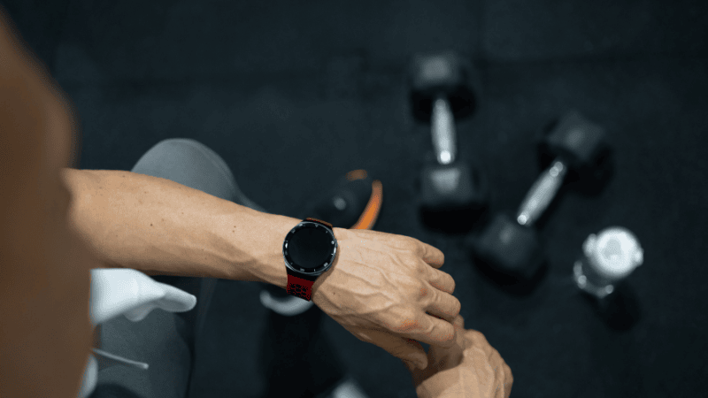 A close-up shot of a workout journal and a pen resting next to a dumbbell, highlighting the importance of tracking reps and sets for progressive overload.